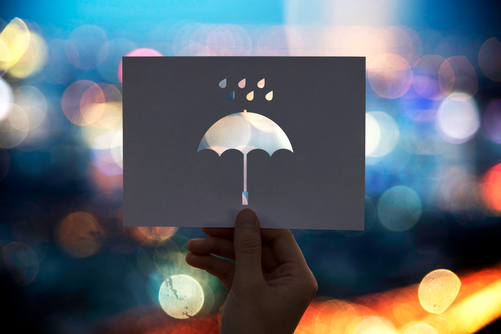 mão segurando papel com recorte em formato de guarda-chuva